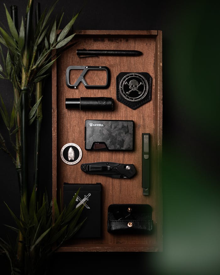 A neatly arranged collection of everyday carry items on a wooden tray with a natural backdrop.